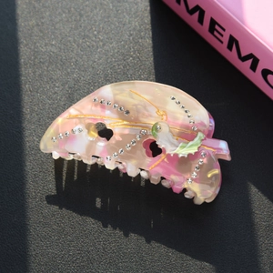 Detail of pink marble acetate hair claw clip with rhinestones and butterfly patterns