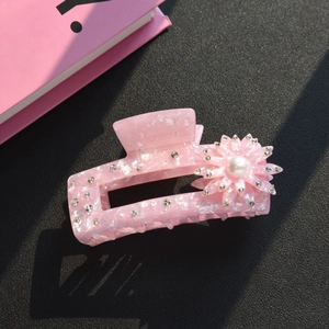 Dettaglio della molletta per capelli in acetato rosa marmorizzato con perla e strass