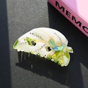 Detail showing marble texture acetic acid hair claw clip with rhinestones in strong light