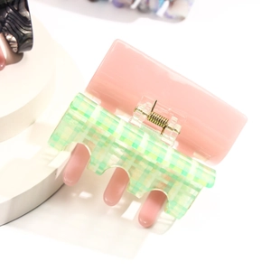 Close-up of pink and light green checkered hair claw clip with golden metal spring