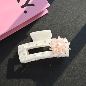 Dettaglio della molletta rettangolare bianco perlato con fiore rosa e strass luccicanti
