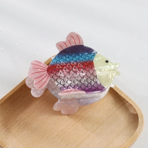 Détail d'une pince à cheveux en forme de poisson avec écailles colorées et fini nacré