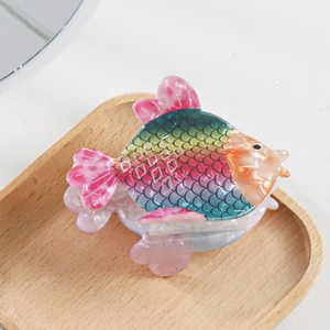Détail d'une pince à cheveux en forme de poisson coloré avec écailles arc-en-ciel et nageoires
