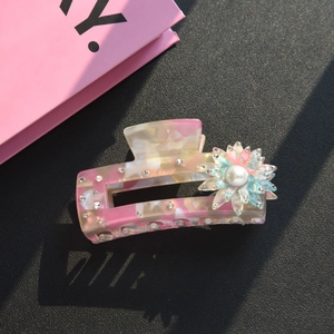 Dettaglio della pinza per capelli a fiore in acetato con strass e perla elegante