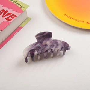 Détail d'une pince à cheveux à texture marbrée violette dans un décor élégant