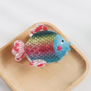 Détail d'une pince à cheveux en forme de poisson arc-en-ciel avec écailles colorées