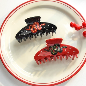 Detail of snake-shaped hair claws with rhinestones on a decorative ceramic plate