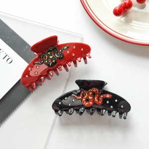 Macro view of snake hair claw clips with gold celestial patterns and inlaid rhinestones