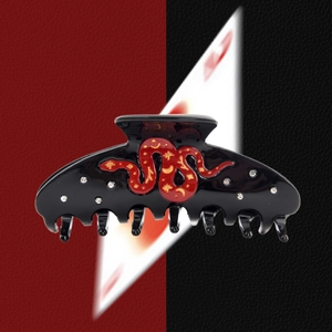 Close-up of black acetate hair claw clip featuring red snake and crystal details