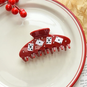 Detailed view of dark red hair claw with poker card patterns and sparkling rhinestones