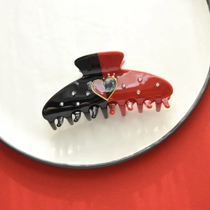 Close-up of heart poker pattern hair claw clip with rhinestones on a white plate