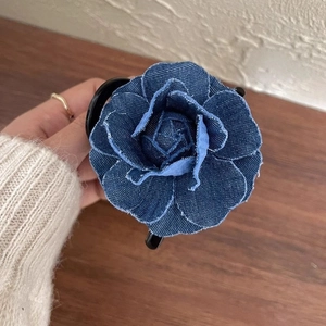 Close-up of denim camellia flower hair claw showing blue fabric texture and fringe detail