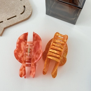Gros plan de pinces à cheveux marbrées rose et orange avec ressorts dorés haut de gamme