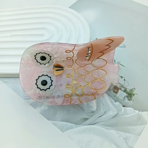 Pince à cheveux chouette en acétate rose marbré avec motifs dorés et strass