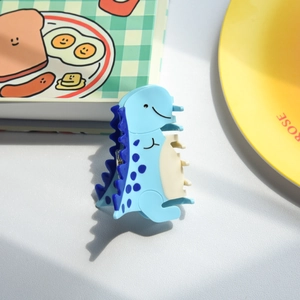 Detalle de una pinza para el pelo de dinosaurio azul con detalles en crema y aletas