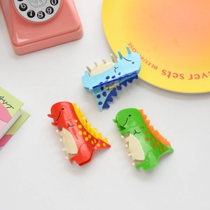 Primer plano de tres pinzas para el pelo de dinosaurio de colores rojo verde y azul