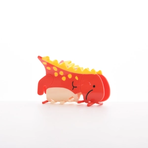 Détail d'une mignonne pince à cheveux dinosaure rouge avec pointes jaunes sur fond blanc