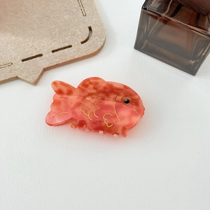 Vue détaillée d'une pince à cheveux carpe koï orange avec texture marbrée et détails dorés