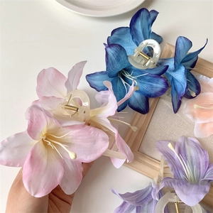 Macro detail of artificial lily flower hair claw clips with realistic silk cloth texture
