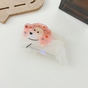 Détail d'une pince à cheveux en forme de chien avec des strass colorés sur fond blanc