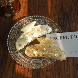 Detailed view of two acetate hair claws with marble texture and rhinestones on glass
