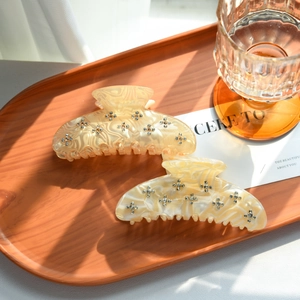 Close-up of marble-textured acetate hair claws with rhinestone floral detail