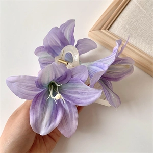 Detailed close-up of a large purple lily floral hair claw clip with a resin base
