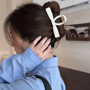 Elegant white marble pattern bow hair claw clip for bun styling on female model