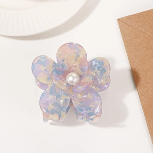 Detail shot of a macaron-colored acetate flower hair claw with a pearl center accent