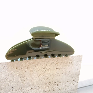 Détail macro de la pince à cheveux en acétate vert olive foncé avec texte doré Barrette La France