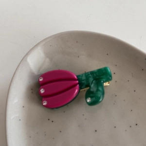 Macro view of pink tulip hair clip with rhinestones on a ceramic dish
