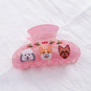Gros plan sur la pince à cheveux rose marbrée avec motifs de chiens mignons et houx