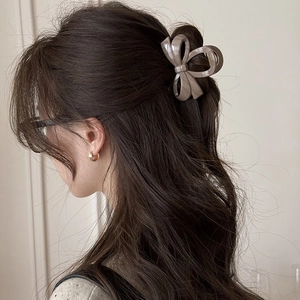 Model wearing a caramel bow hair claw clip in wavy hair for an elegant updo hairstyle