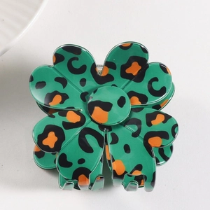 Detail of green flower hair claw clip with orange leopard print on acrylic material