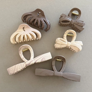 Flat lay of marble texture hair claws in cream, brown and pink acetate material