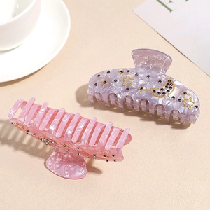 Detailed macro view of acetate hair claws with gold star and moon rhinestone accents