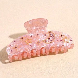 Macro shot of pink marble hair claw clip with rhinestones and gold moon star charms