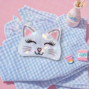 Détail de la pince à cheveux chat irisée sur fond de tissu à carreaux bleus