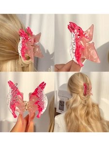 Pince à cheveux dinosaure en acétate rose et blanc avec détails et coiffure sur modèle