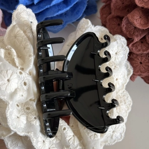 Gros plan sur la pince à cheveux noire brillante avec ressort métallique et grandes dents