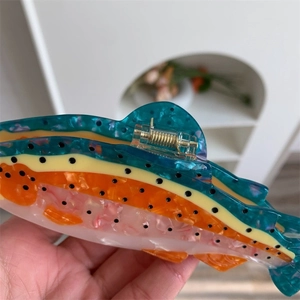 Detail of fish-shaped acetate hair claw with vibrant color gradients and metal spring