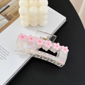 Detail of square hair claw clip with pink cherry blossom flowers and gold spring