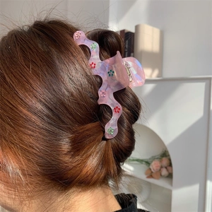Pince à cheveux fleurie en acétate rose translucide avec strass sur coiffure élégante