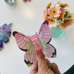 Dettaglio della clip per capelli a farfalla rosa e verde con molla in metallo dorato