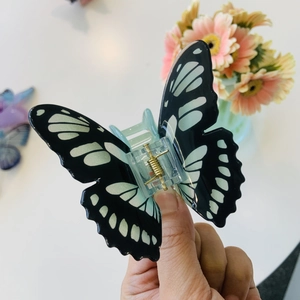 Dettaglio del fermaglio a farfalla con texture floreale e molla in metallo dorato
