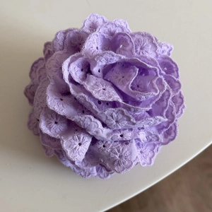 Détail d'une pince à cheveux fleur en dentelle violette avec broderie et design de rose