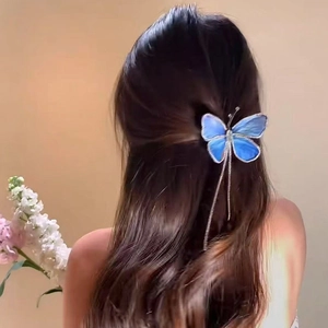 Detailansicht einer blauen Schmetterlings-Haarklammer mit langen Quasten am Haar