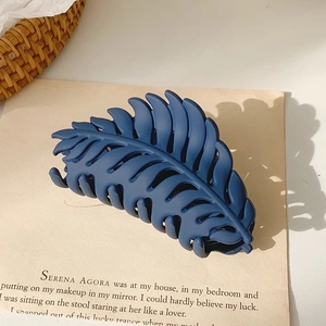 Macro detail of navy blue leaf-shaped matte hair claw clip with multi-tooth design