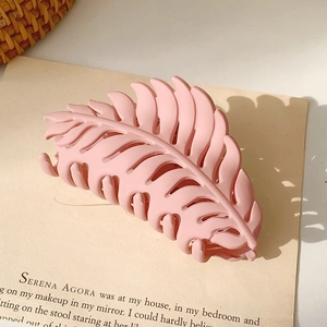 Detail view of a matte pink leaf-shaped hair claw clip on vintage background paper