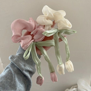 Détail de chouchous plissés tulipe avec de longs rubans et breloques florales roses et blancs